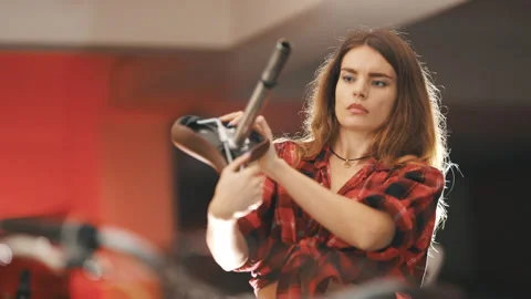 Focused woman mechanic assembling bicycle saddle in workshop Stock Footage 328405635