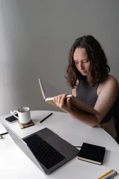 Focused woman reading from a notebook while working at home office desk Stock Photos