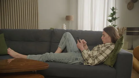Focused Woman Scrolling Tablet Computer and Sitting Sofa 動画素材 278681331