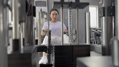 Focused woman strength training on rowing machine in gym facility Stock Footage 307796080