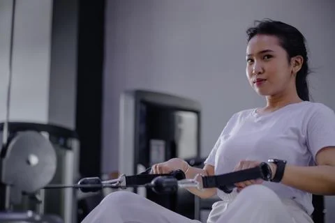 Focused woman training on rowing machine in gym for fitness goals Stock Photos