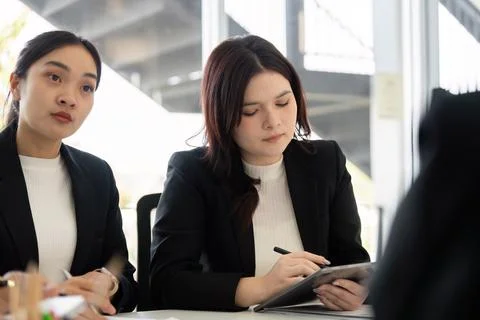 Focused Work and Collaboration. A young woman taking notes during a team meeting Foto stock