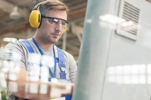 Focused worker in protective workwear at computer in factory Stock Photos