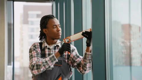 Focused worker sealing window with caulking gun Stock Footage 309484162