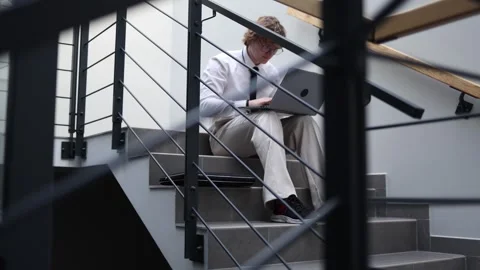 Focused worker using laptop on stairs Stock Footage 333975192