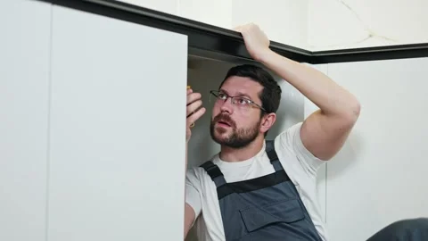 Focused workman holding countertop while installing water system in cabinet Video stock 266380981