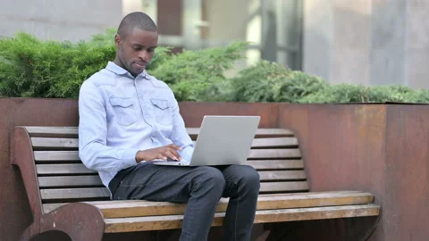 Focused Young African Man using Laptop Outdoor Stock Footage 136031435
