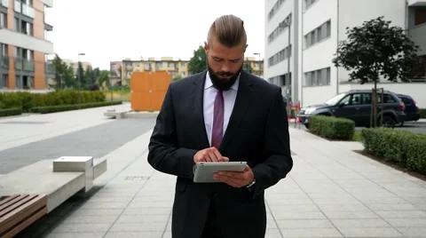 Focused young bearded businessman using his tablet pc. Outdoor photo Stock Footage 56526564