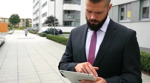 Focused young bearded businessman using his tablet pc. Outdoor photo. Stock Footage 60944797