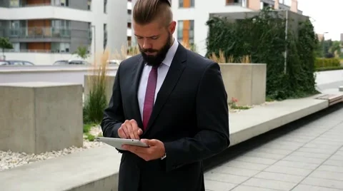 Focused young bearded businessman using his tablet pc. Outdoor photo. Stock Footage 60944815