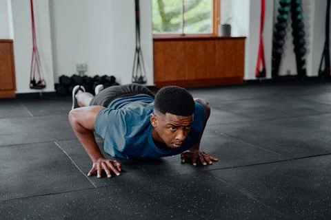 Focused young black man doing push-ups at the gym Stock Photos