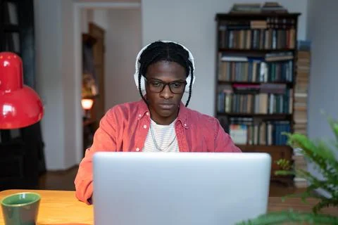 Focused young black man remote worker wearing headphones listening to music Stock Photos