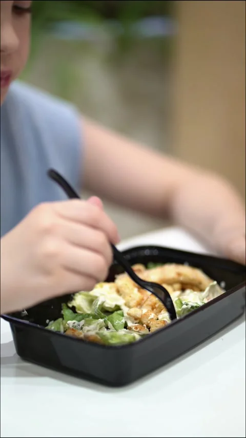Focused young boy enjoying a Caesar salad during lunch at a food court Video stock 340931996