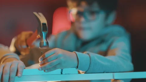Focused young boy hammering a nail into wood Stock Footage 329556290