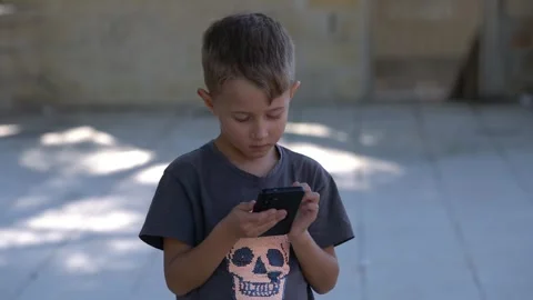 Focused young boy using smartphone outdoors in daylight Stock-Footage 340336845