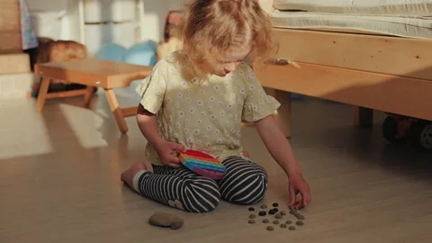 Focused Young Child Engaged in Sensory Play with Colorful Fidget Toy and Small Stock Footage 336464691