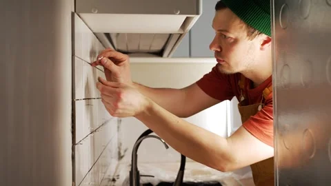 Focused young construction worker carefully applying grout to the seams of a Stock Footage 344566747