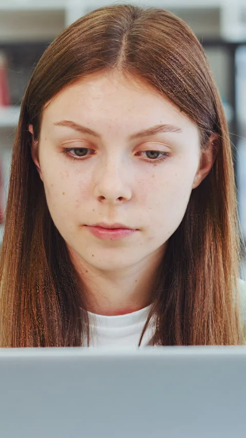 Focused young female student using laptop for studying in college library Stock Footage 346814989