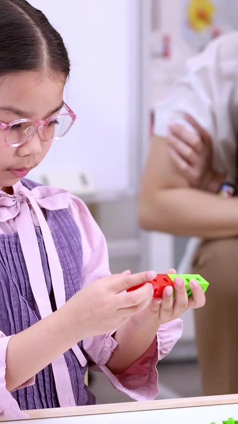 Focused Young Girl Playing with Interlocking Math Cubes in Classroom 库存影片 330995535
