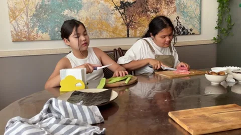 Focused young girls learning to handle kitchen tools and ingredients, showcasing 動画素材 279923506