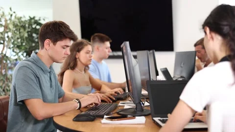 Focused young guy studying in computer lab with fellow students engrossed in Stock Footage 263114708
