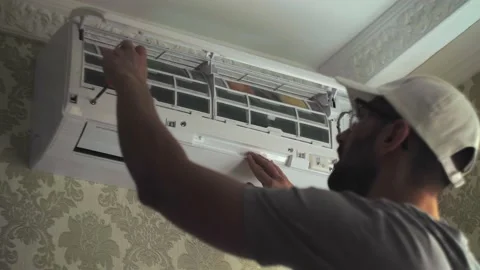 Focused young handyman using screwdriver on white air conditioner unit on wall Stock Footage 220833892