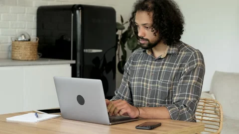 Focused young indian man using laptop, typing on keyboard, writing email Stock Footage 187059495