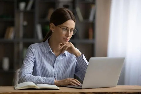 Focused young lady engaged in computer job at home office Stock Photos