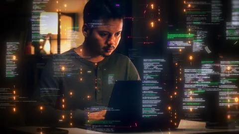 Focused young male developer working on a laptop at night surrounded by flo.. Foto stock