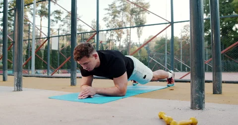 A Focused Young Man Engaged in Performing the Plank Exercise Outdoors for Stock Footage 318073972