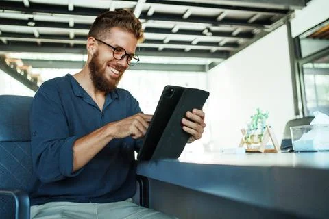 A focused young man is engaging with a tablet in a stylish and modern Stock Photos
