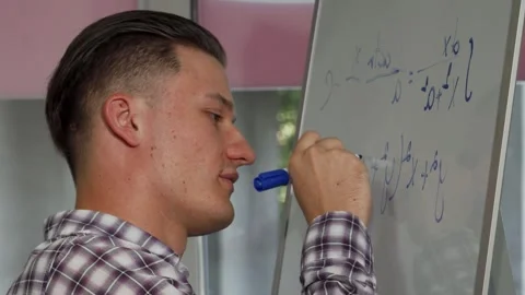 Focused young man enthusiastically solving math problems on a whiteboard Stock Footage 311539868