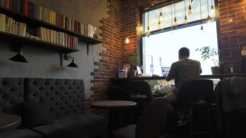 A Focused Young Man Enthusiastically Working Within a Cozy Cafe Environment Vídeo Stock 281106656
