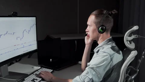 Focused young man in headset trading stocks online late at night Stock Footage 311643107