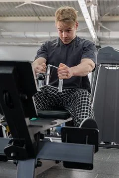 Focused young man performing intense seated rowing machine workout in modern Stock Photos