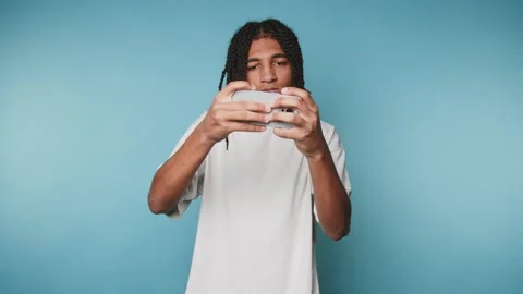 Focused young man plays with a smartphone, revealing concentration and enga.. Stock Footage 313280055