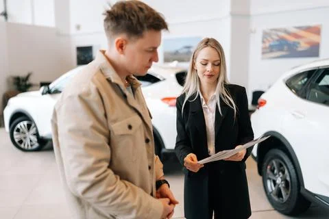Focused young man reading technical specifications of auto at modern showroom Stock Photos