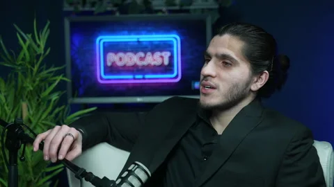 Focused young man speaking into a microphone during a talk show interview with Stockbeeldmateriaal 336044081