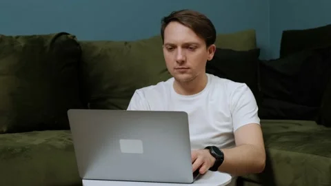 Focused young man studying or working on laptop sit on floor in living room. Stock Footage 146904786