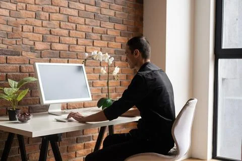 Focused young man using laptop, typing on keyboard, writing email or message Foto stock