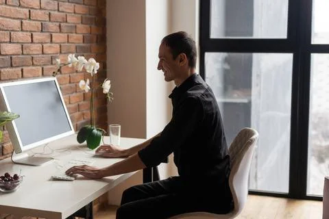 Focused young man using laptop, typing on keyboard, writing email or message 스톡 사진