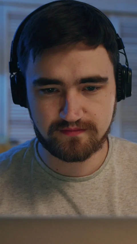 A Focused Young Man Working Diligently on His Laptop Simultaneously While Stock Footage 313786079