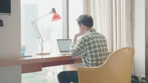 Focused Young Man Working from Home with a City View Stock Footage 319415113