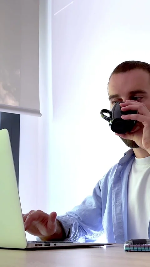 Focused young man working from home on a laptop computer, taking a short break Stock Footage 345117296