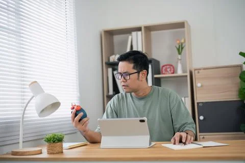 Focused young man working from home holding timer and using digital tablet .. Stock Photos
