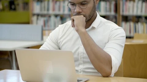 Focused young man working with laptop in library. Video stock 116774544