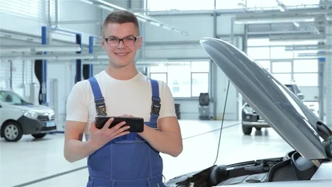 Focused young mechanic analyzing data on his tablet in a bright car service Stock Footage 311826270