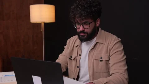 Focused young professional man working on laptop computer at night Stock Footage 346988976