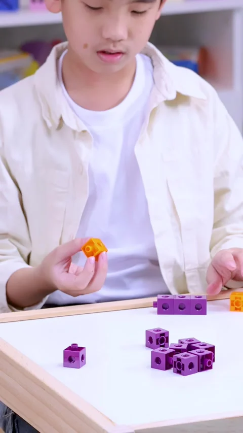 Focused Young Student Connecting Colored Math Cubes at a Desk Stock Footage 325298103