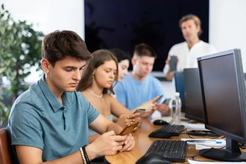Focused young student using smartphone while studying in computer workshop 스톡 사진